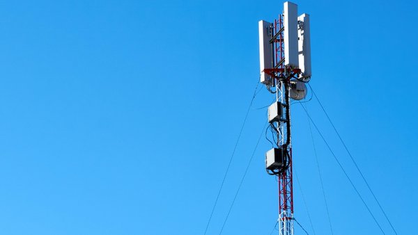 A photograph of a telecommunications tower, set against the background of a blue sky